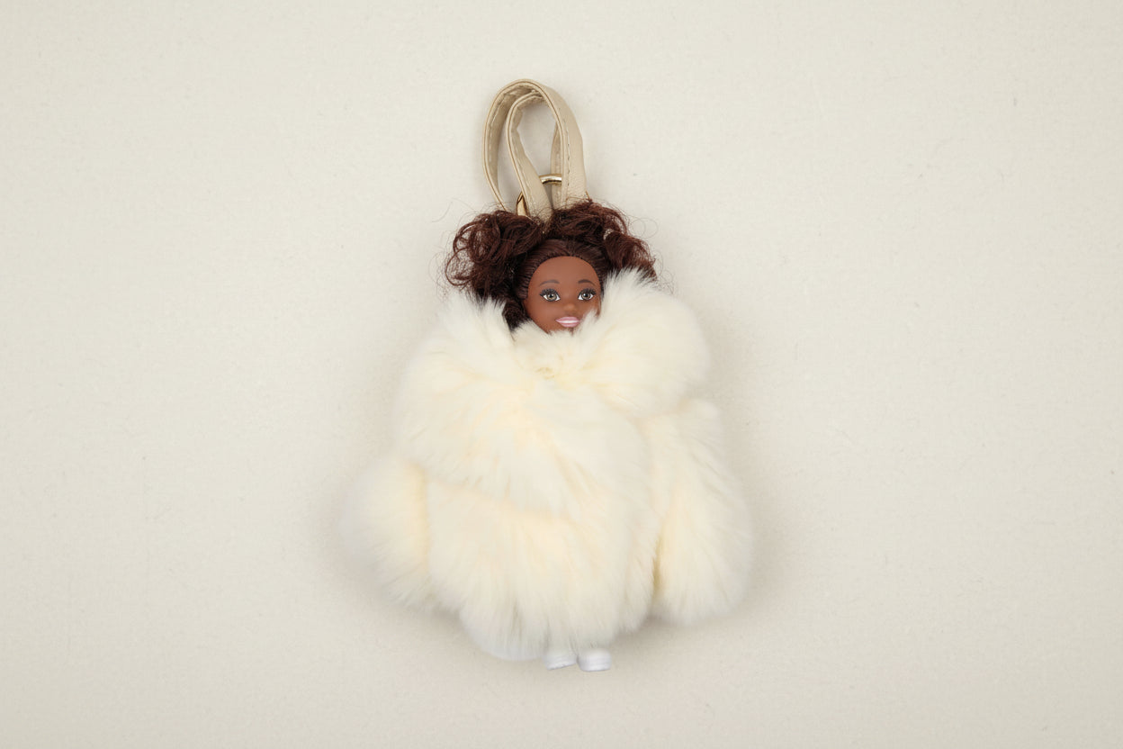 Doll with brown hair wearing a white fur coat on a white background