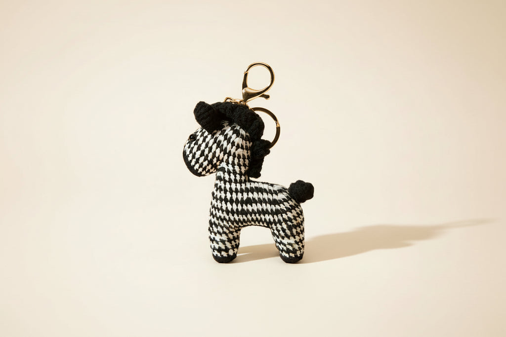 Zebra-shaped keychain with houndstooth pattern on a beige background