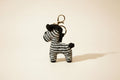 Zebra-shaped keychain with houndstooth pattern on a beige background