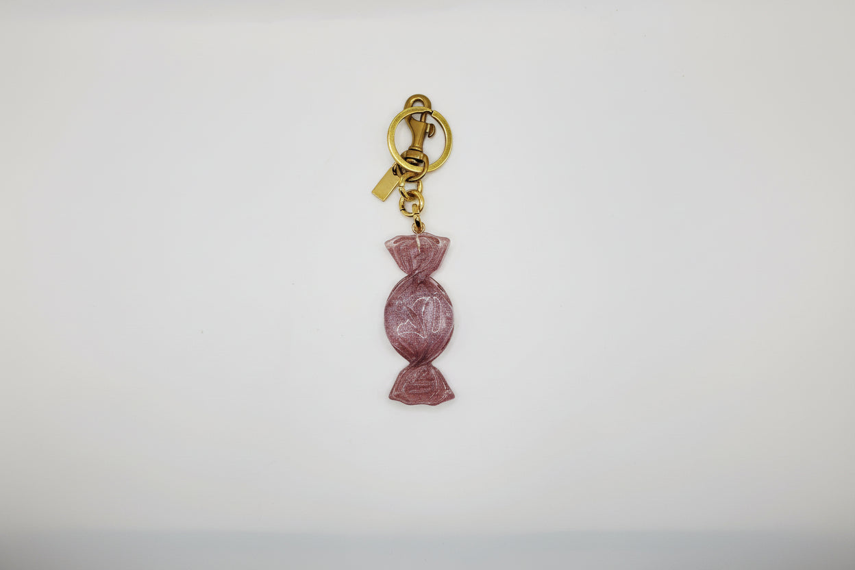 Pink candy-shaped keychain with gold chain on a white background
