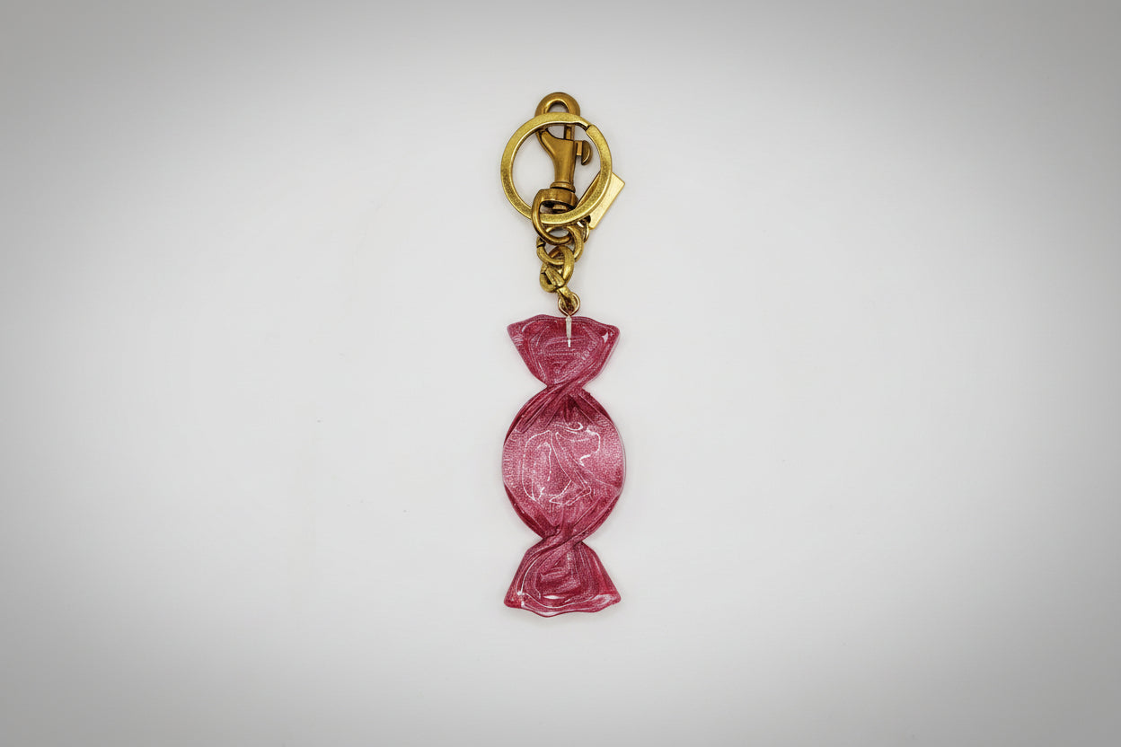 Pink candy-shaped keychain with gold clasp on a white background