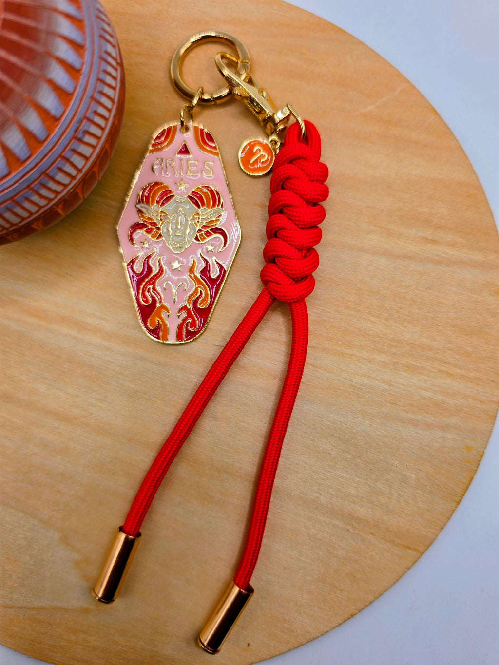 Keychain with red cord and decorative tag on a wooden surface