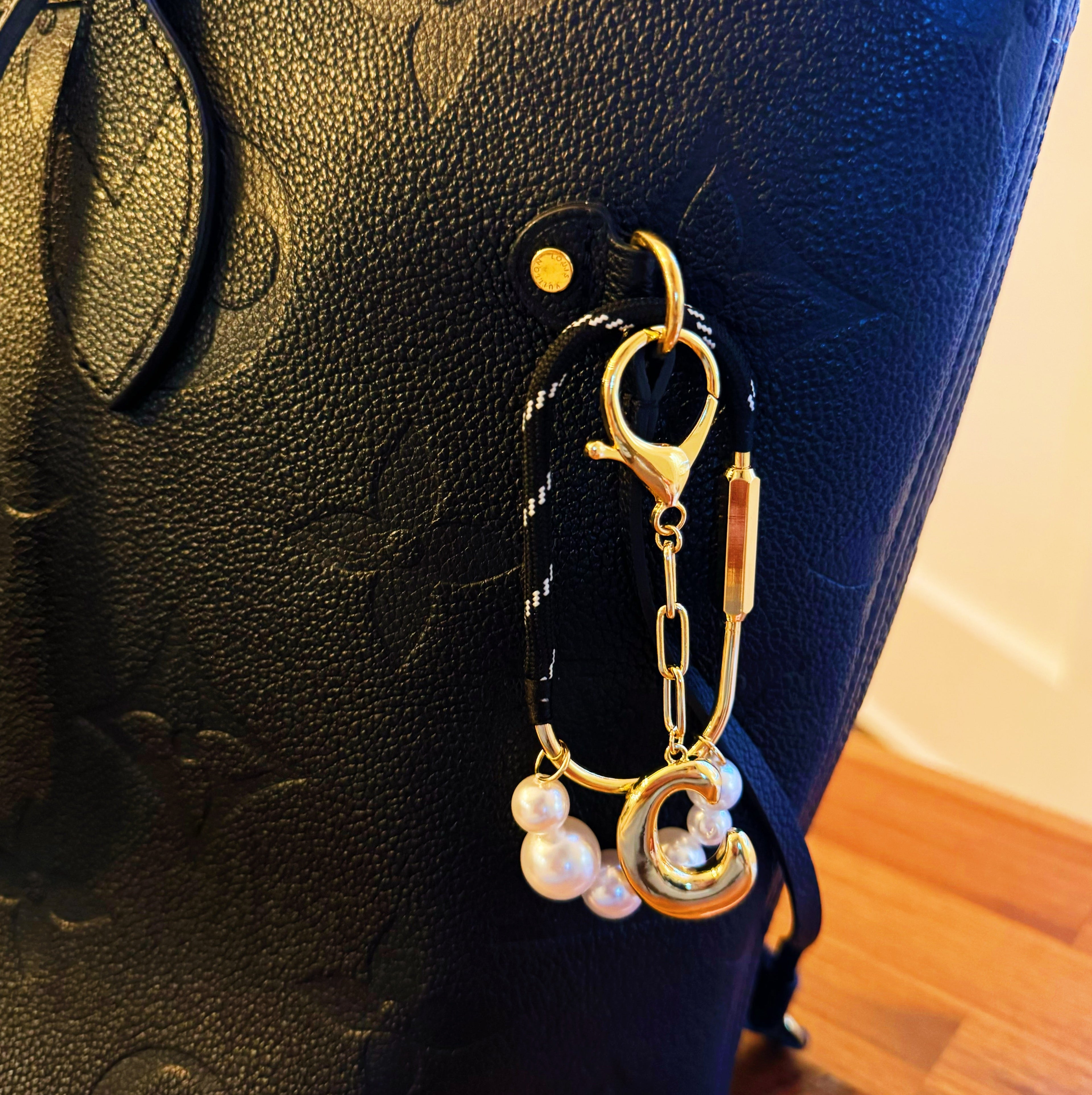 Gold keychain with pearls attached to a black textured surface