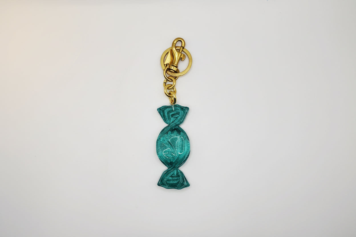 Teal candy-shaped keychain with gold clasp on a white background