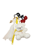 White teddy bear keychain with red hearts and black bow on a beige background