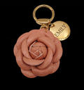Pink rose-shaped keychain with gold ring and 'EMILY' tag on black background