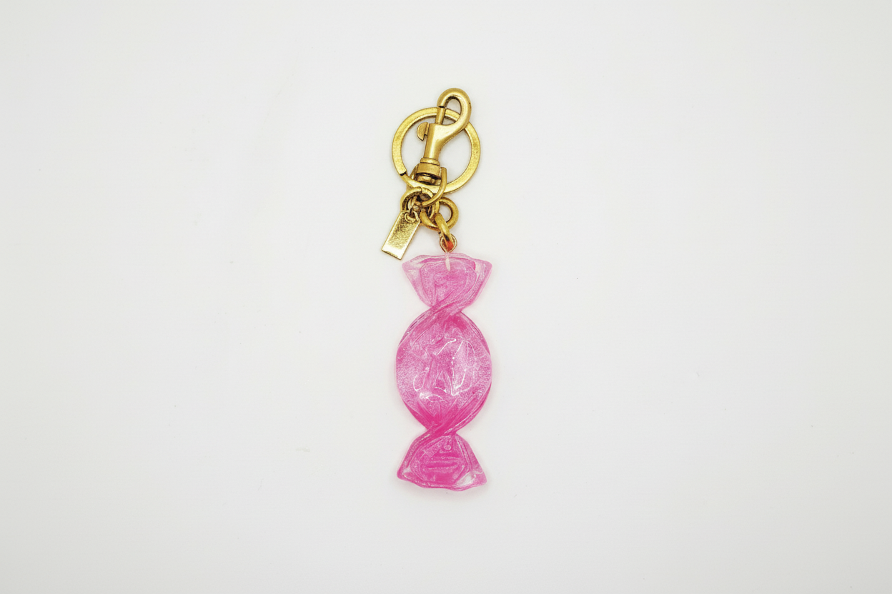 Pink candy-shaped keychain with gold clasp on a white background