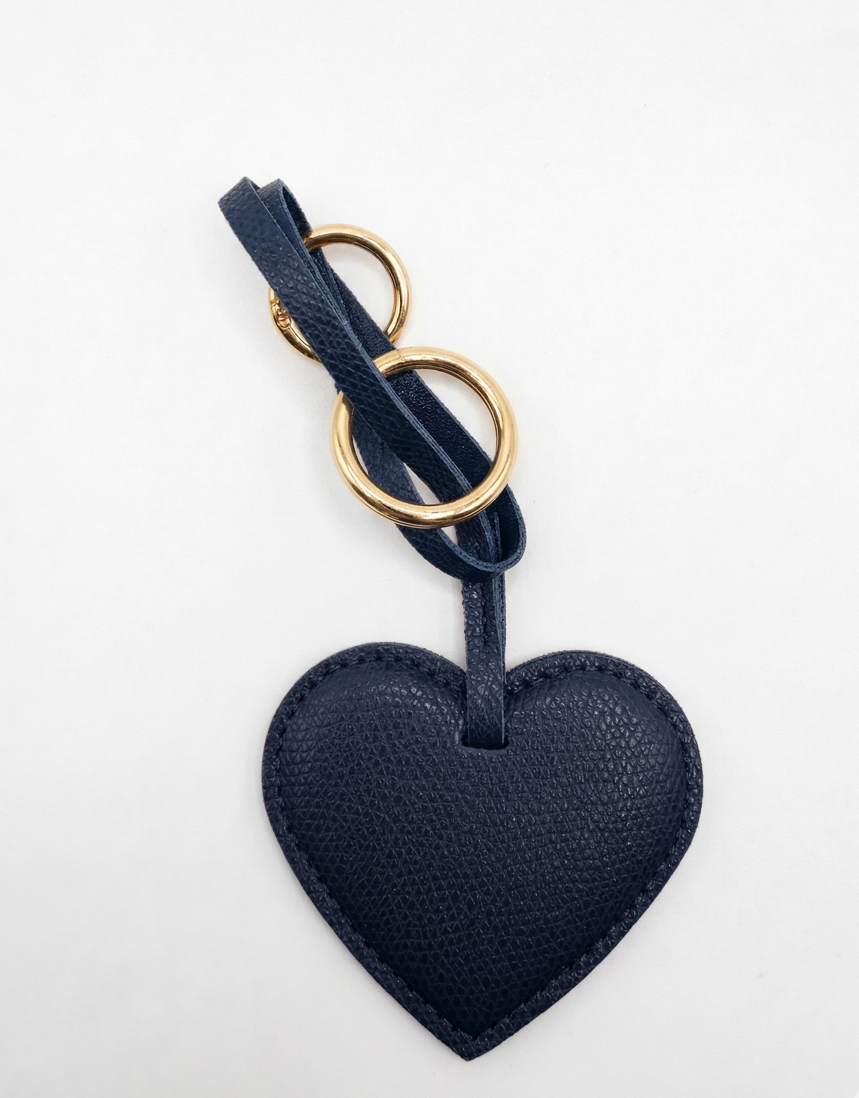 Navy blue heart-shaped keychain with gold ring on a white background