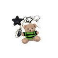 Teddy bear keychain with green sweater and black star charm on a white background